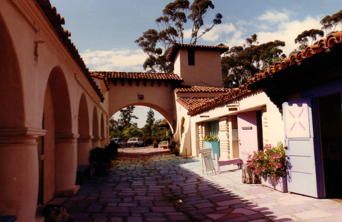 Blick bei Tageslicht auf den farbenfrohen Fliesenhof des Spanish Village Art Center mit Bogenarkaden und Ateliertüren im Balboa Park, San Diego.