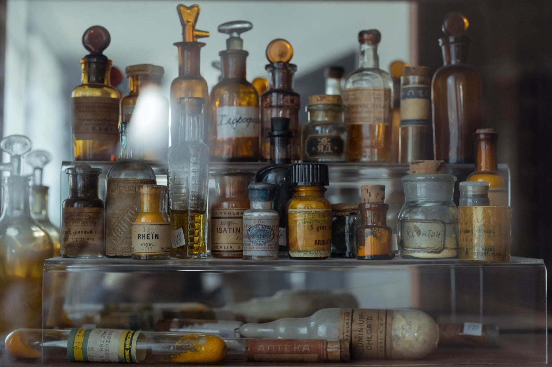 Eine Sammlung alter Glasflaschen und Phiolen mit verblassten Etiketten, arrangiert in einem antiken Alchemistenlabor – eine geheimnisvolle, historische Atmosphäre.