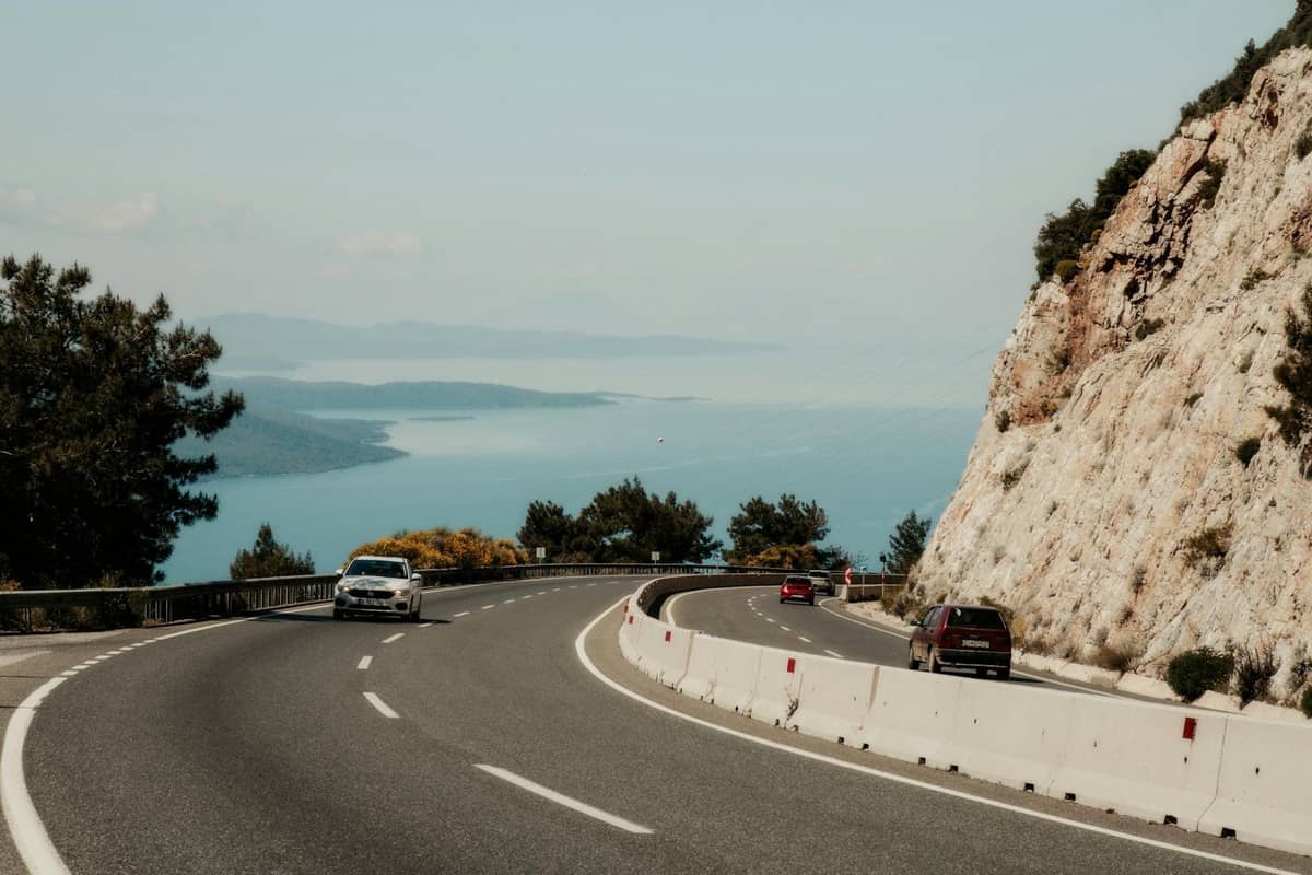Coastal road with cars driving along a cliffside, overlooking the blue Adriatic Sea near Split, Croatia.