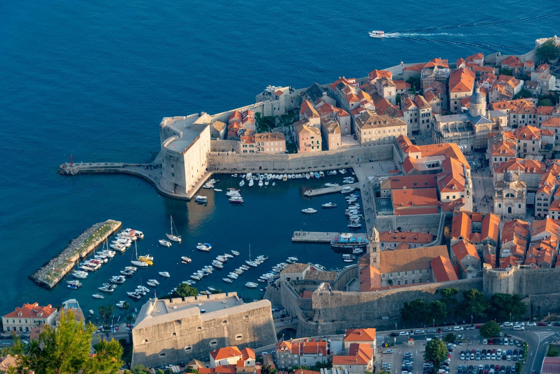 Vista aérea del puerto antiguo de Dubrovnik con murallas de piedra, marina y barcos, con vistas al azul mar Adriático.