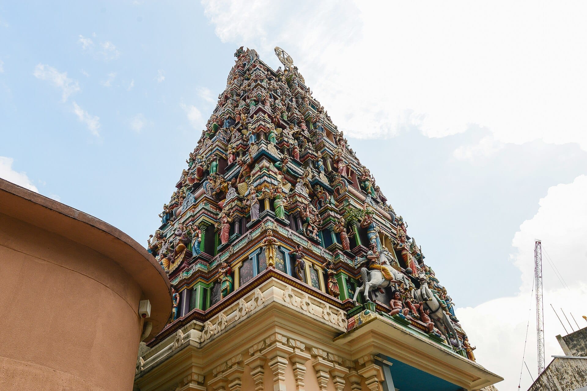 Sri Mahamariamman Temple's colorful, intricately carved entrance tower stands tall against a bright sky in Kuala Lumpur's Chinatown.
