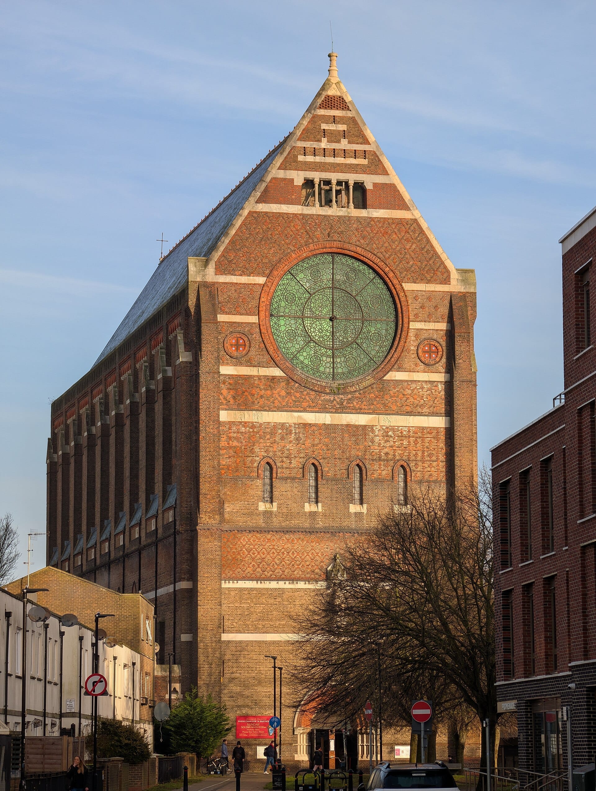 St Bartholomew's Church in Brighton, a towering Victorian brick building with a large circular stained-glass window, seen on a sunny day.