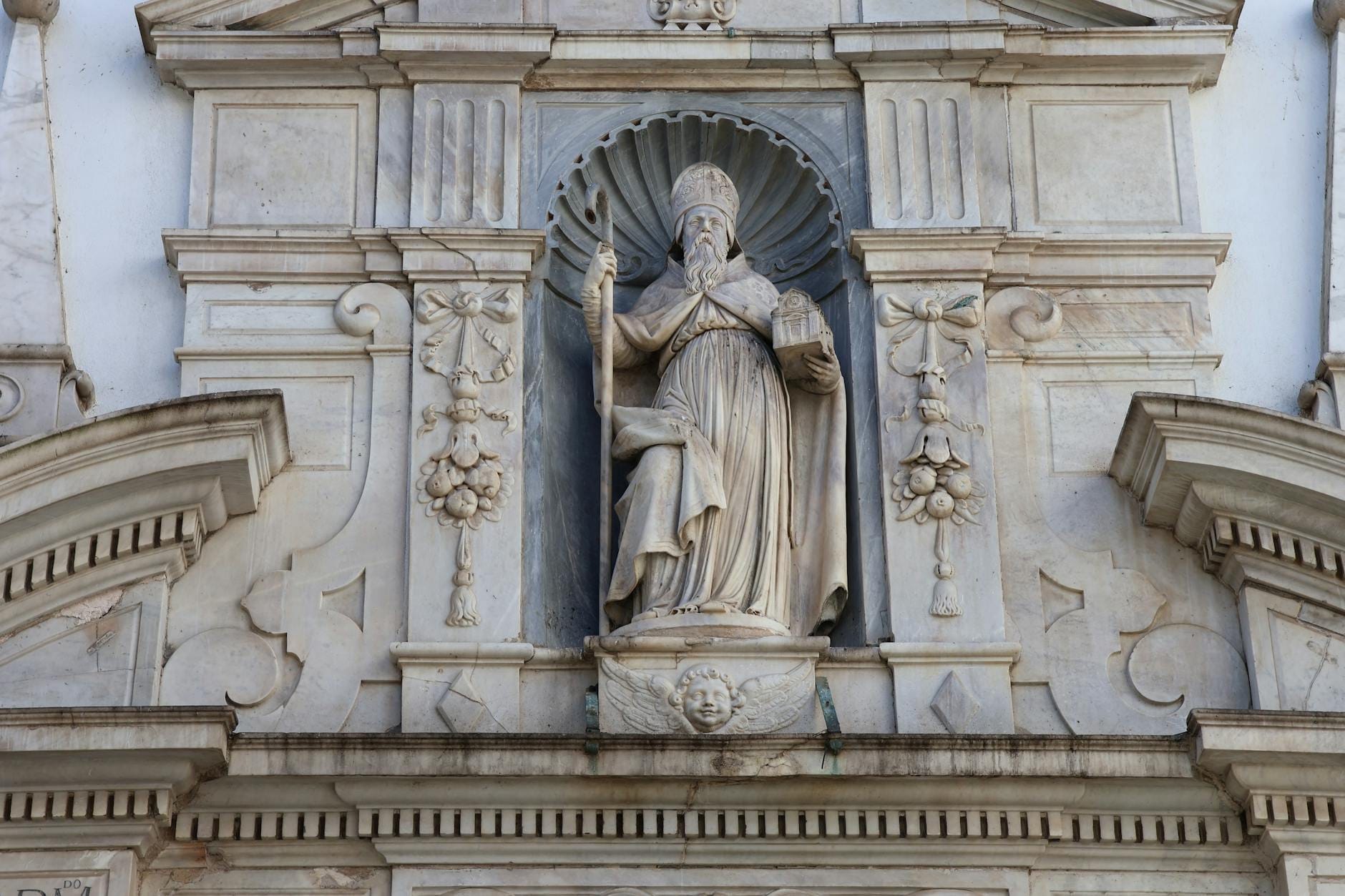 Primer plano de la rica fachada de piedra ornamentada de la Iglesia de San Blas en Dubrovnik, con nichos tallados y detalles barrocos.