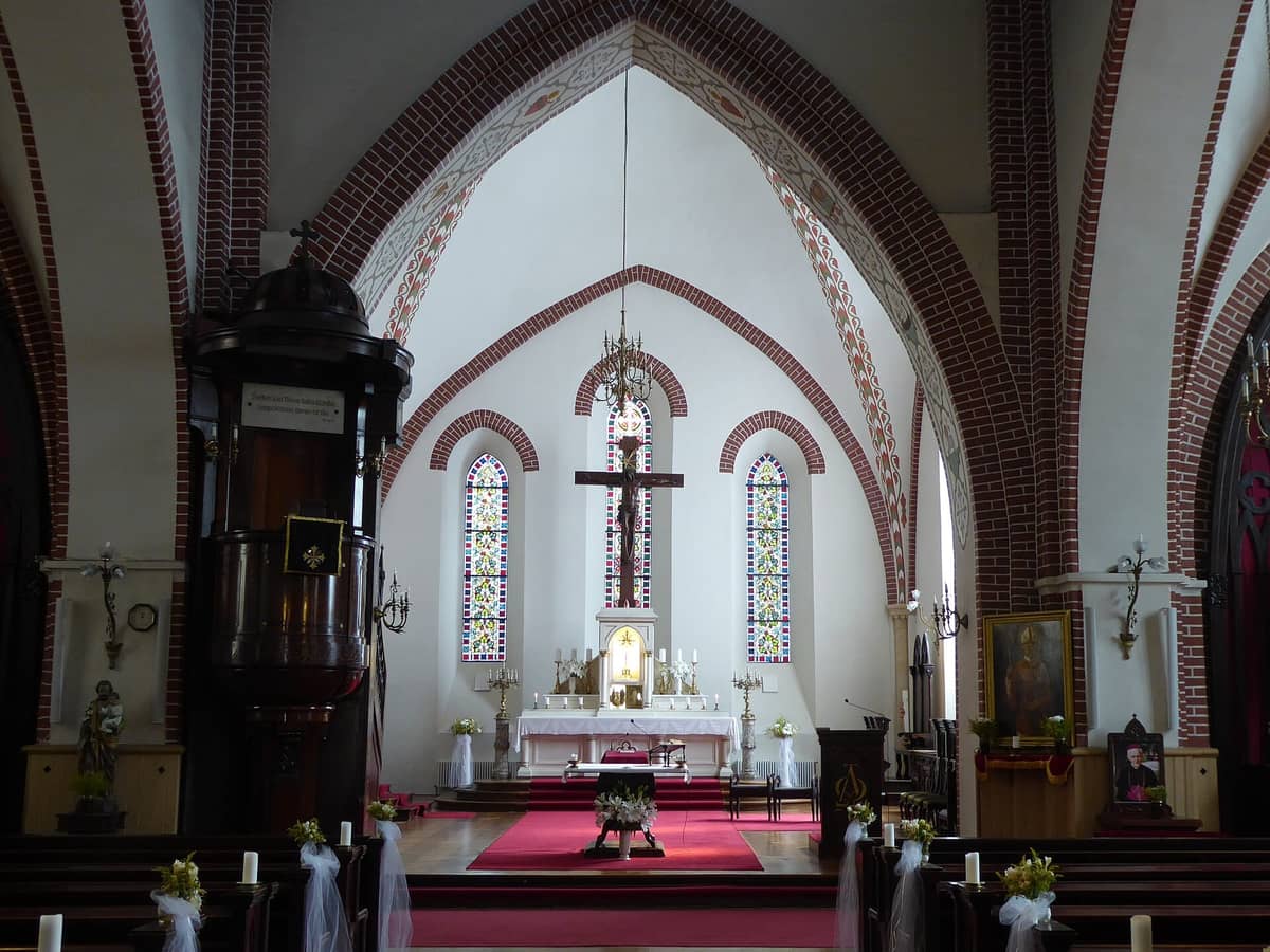 Innenansicht der Jakobskathedrale in Riga mit Blick auf den Altar, die Buntglasfenster und das gemauerte Backsteingewölbe der katholischen Kirche.