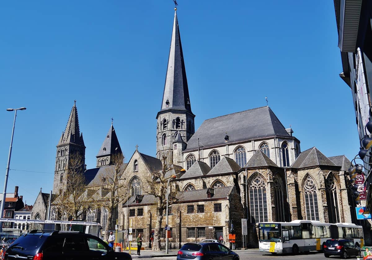 St James' Church (Sint-Jacobskerk) in Ghent features Romanesque and Gothic architecture with tall spires, arched windows, and busy street traffic in front.