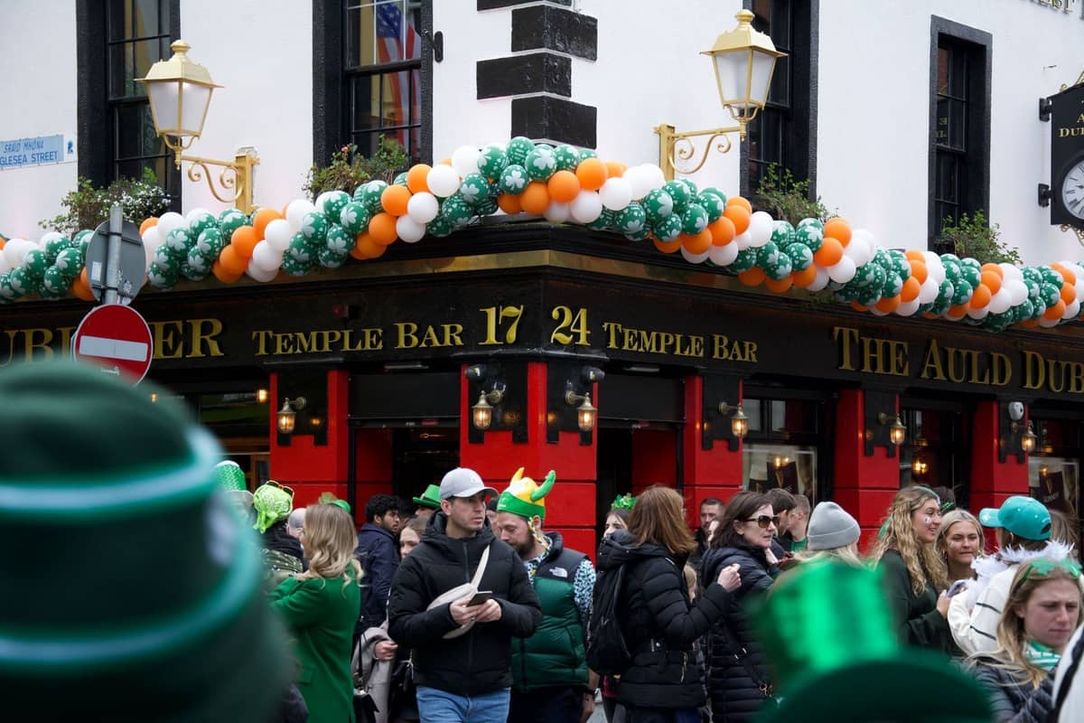 Folla che festeggia il giorno di San Patrizio fuori dal Temple Bar di Dublino, decorato con palloncini verdi, bianchi e arancioni.