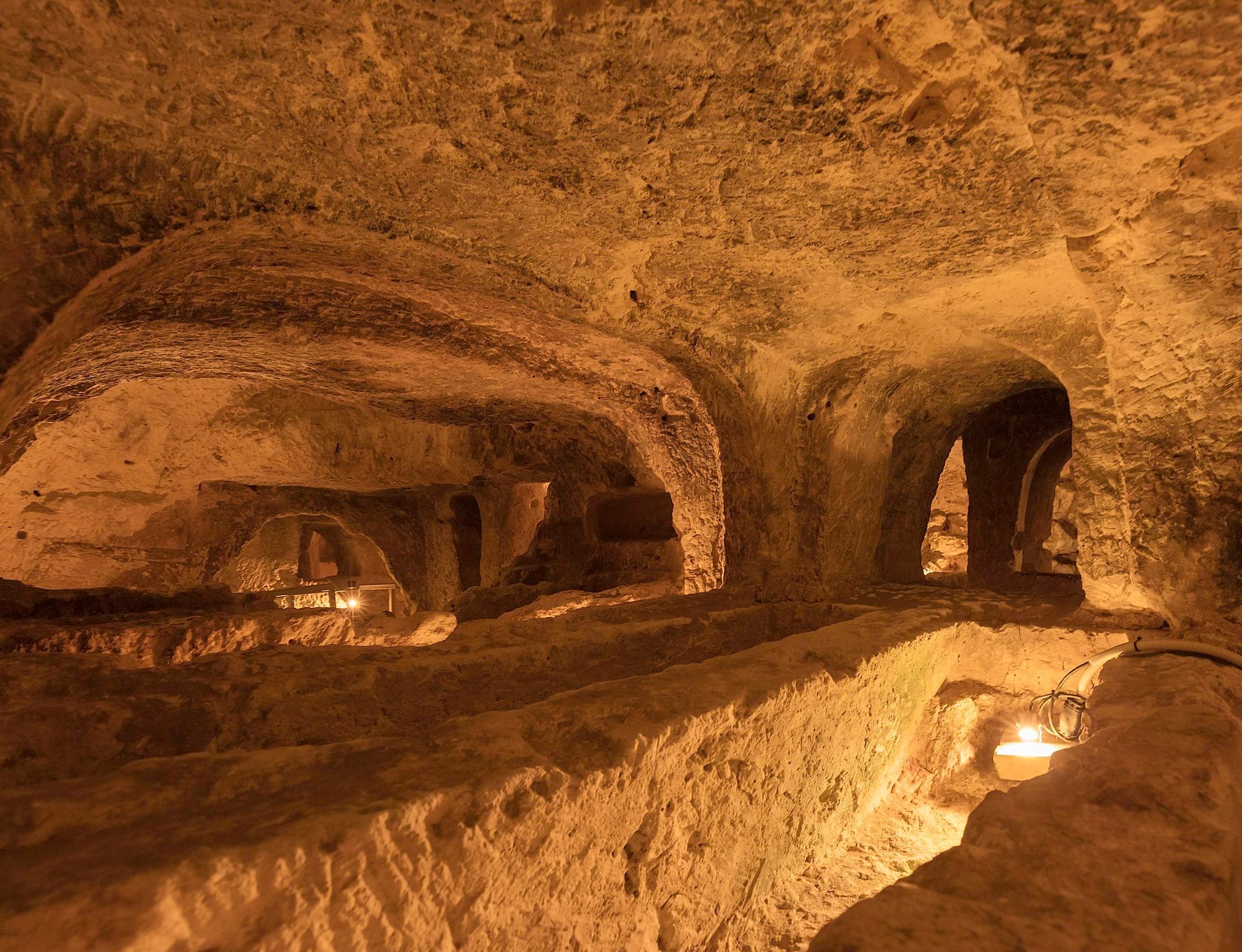 Vista delle Catacombe di San Paolo a Rabat, Malta, con tunnel in pietra calcarea scavati a mano e nicchie funerarie illuminate da una luce calda.