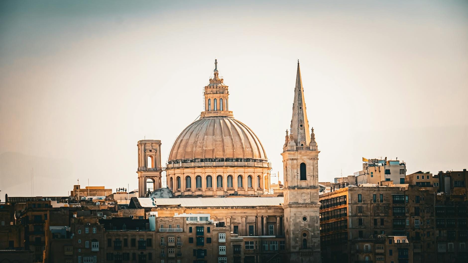 Grande cupola e guglia barocca della Cattedrale di San Paolo a Mdina, Malta, che si eleva sopra gli edifici color miele della città sotto la chiara luce del mattino.