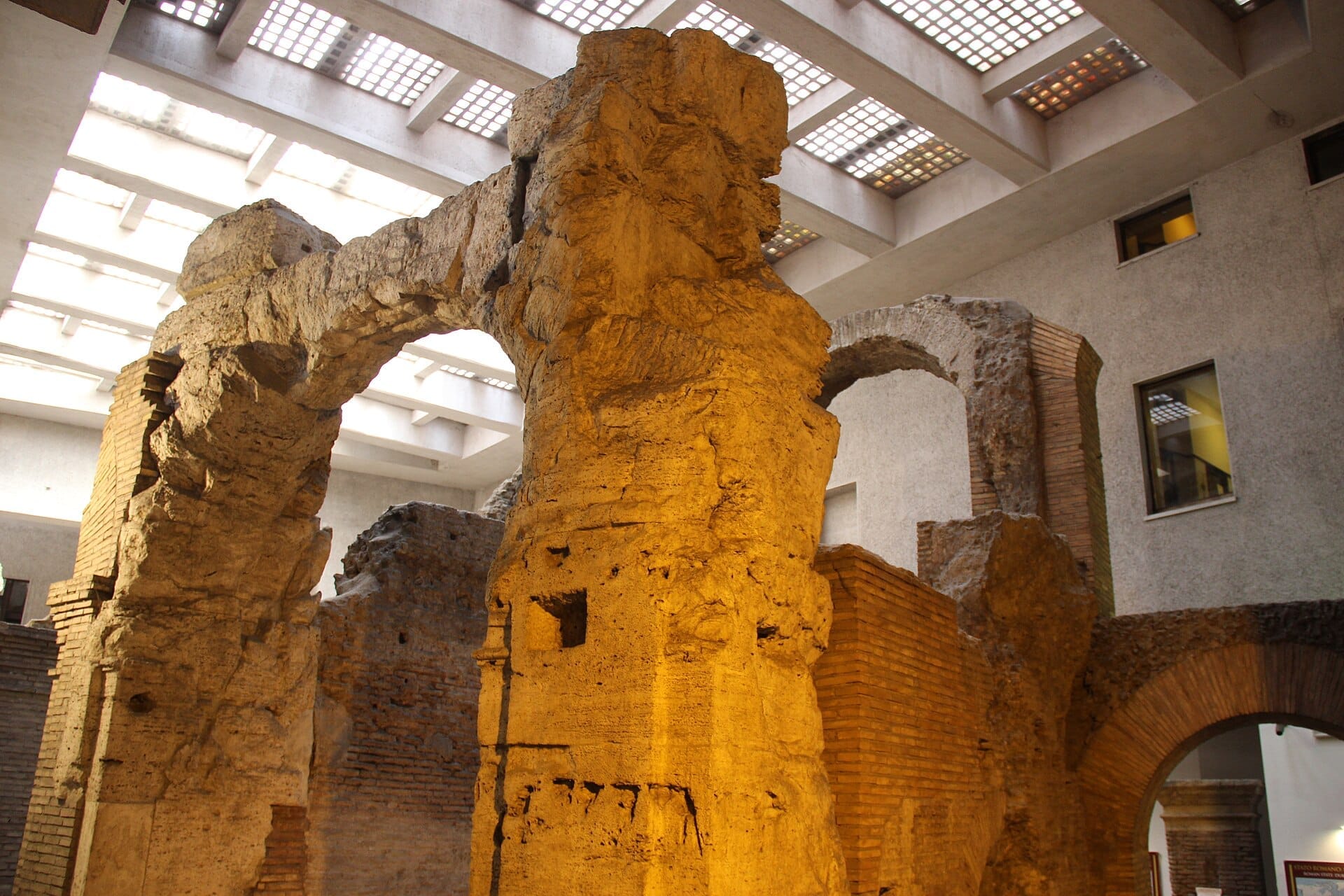Ancient brick and stone arches of the Stadium of Domitian ruins, illuminated by soft indoor lighting beneath a modern skylit ceiling.