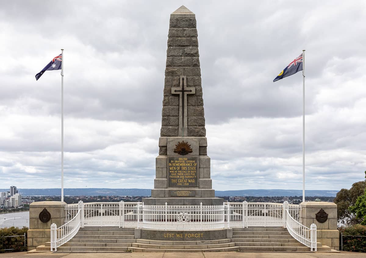 Vista frontal del obelisco del Memorial Estatal de Guerra en Kings Park, Perth, con dos mástiles y el horizonte de la ciudad y el río Swan al fondo.