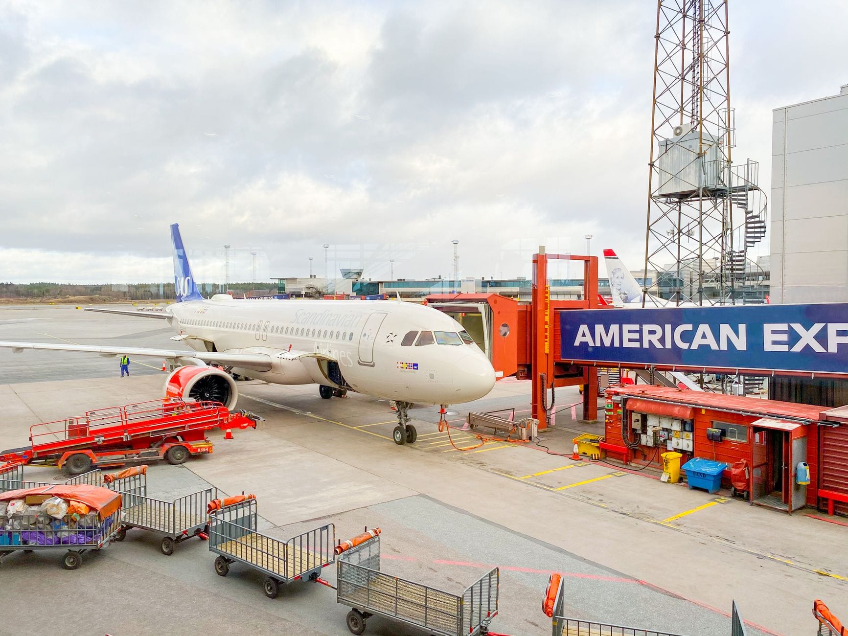 เครื่องบินสายการบิน Scandinavian Airlines จอดที่เกตสนามบินสตอกโฮล์ม อาร์ลันดาพร้อมรถบริการภาคพื้นดินและอาคารเทอร์มินัล