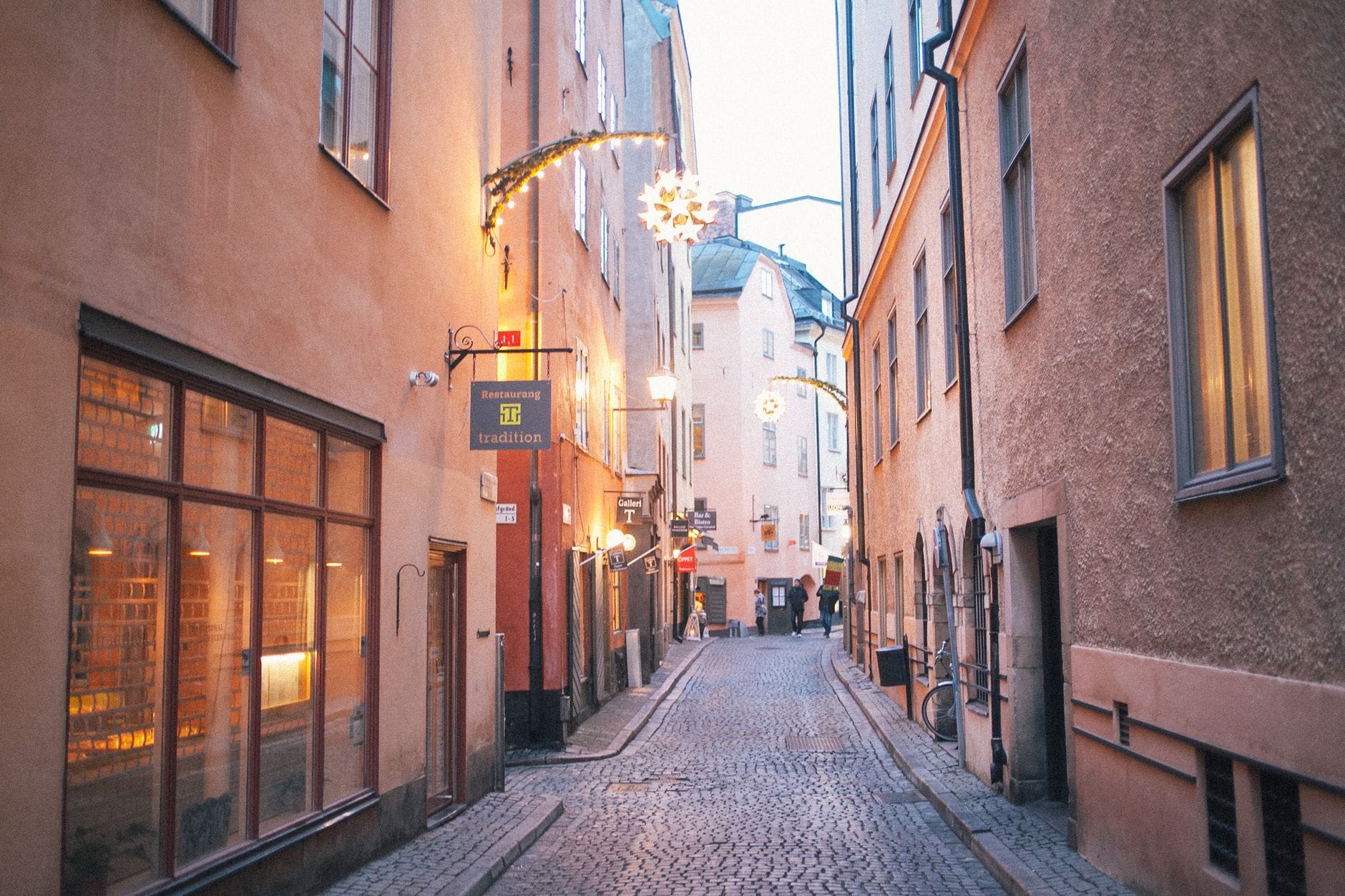 ถนนหินในย่าน Gamla Stan ของสตอกโฮล์มแต่งไฟและดาวคริสต์มาสตลอดสองฝั่ง ล้อมด้วยอาคารเก่าแก่ยามค่ำฤดูหนาว