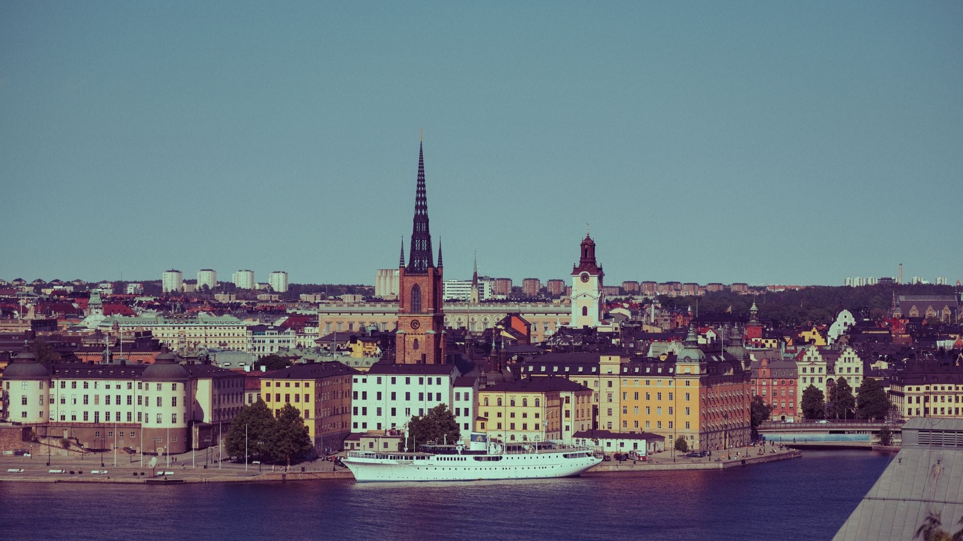 เส้นขอบฟ้าเมืองสตอกโฮล์มแบบคลาสสิกพร้อมโบสถ์ Riddarholmen อาคารสีสันสดใส และเรือท่องเที่ยวบนน้ำในเบื้องหน้า