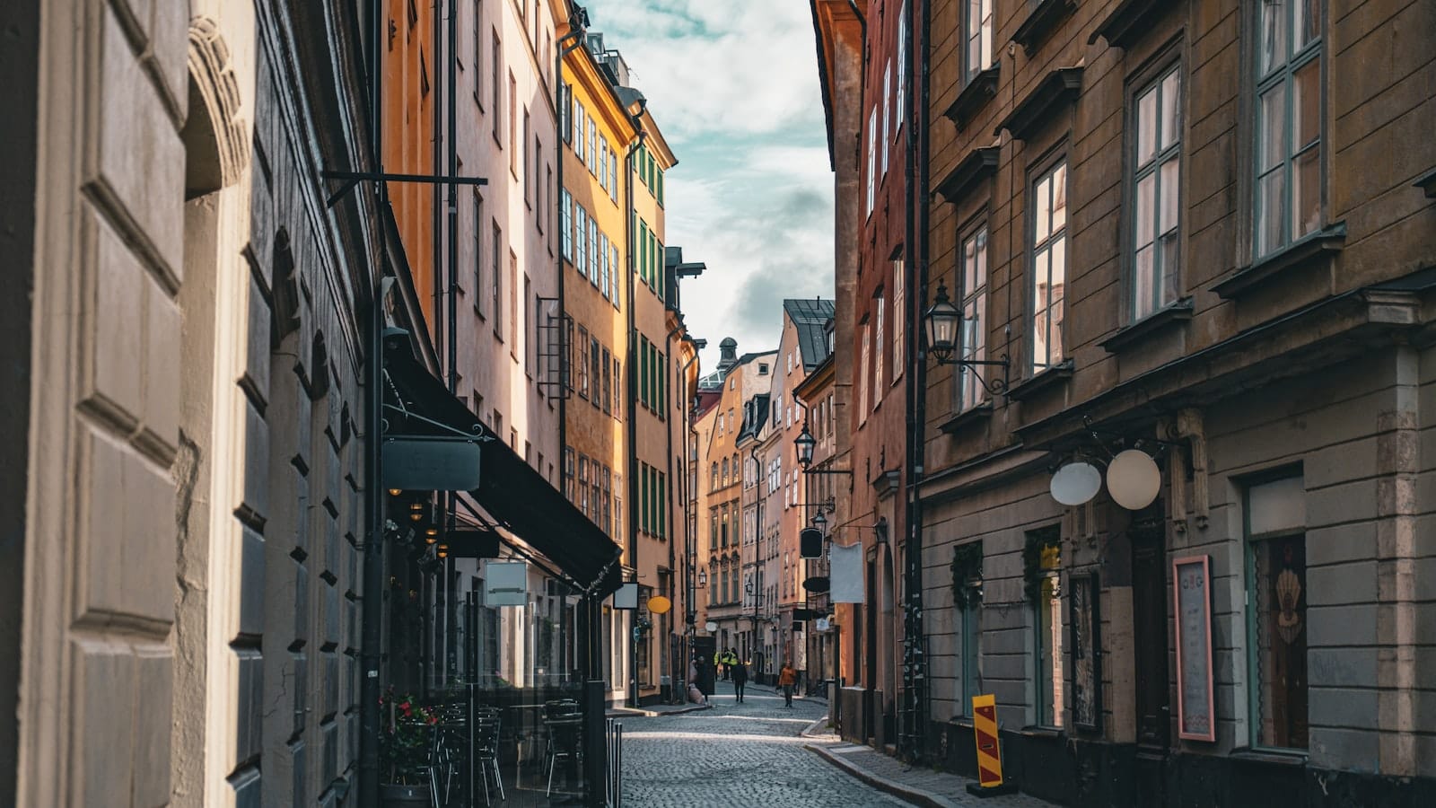 ถนนหินกรวดแคบๆ ที่เรียงรายด้วยอาคารประวัติศาสตร์สีสันสดใสใน Gamla Stan กรุงสตอกโฮล์ม ภายใต้แสงธรรมชาติอ่อนโยนและไม่มีฝูงชนให้เห็น
