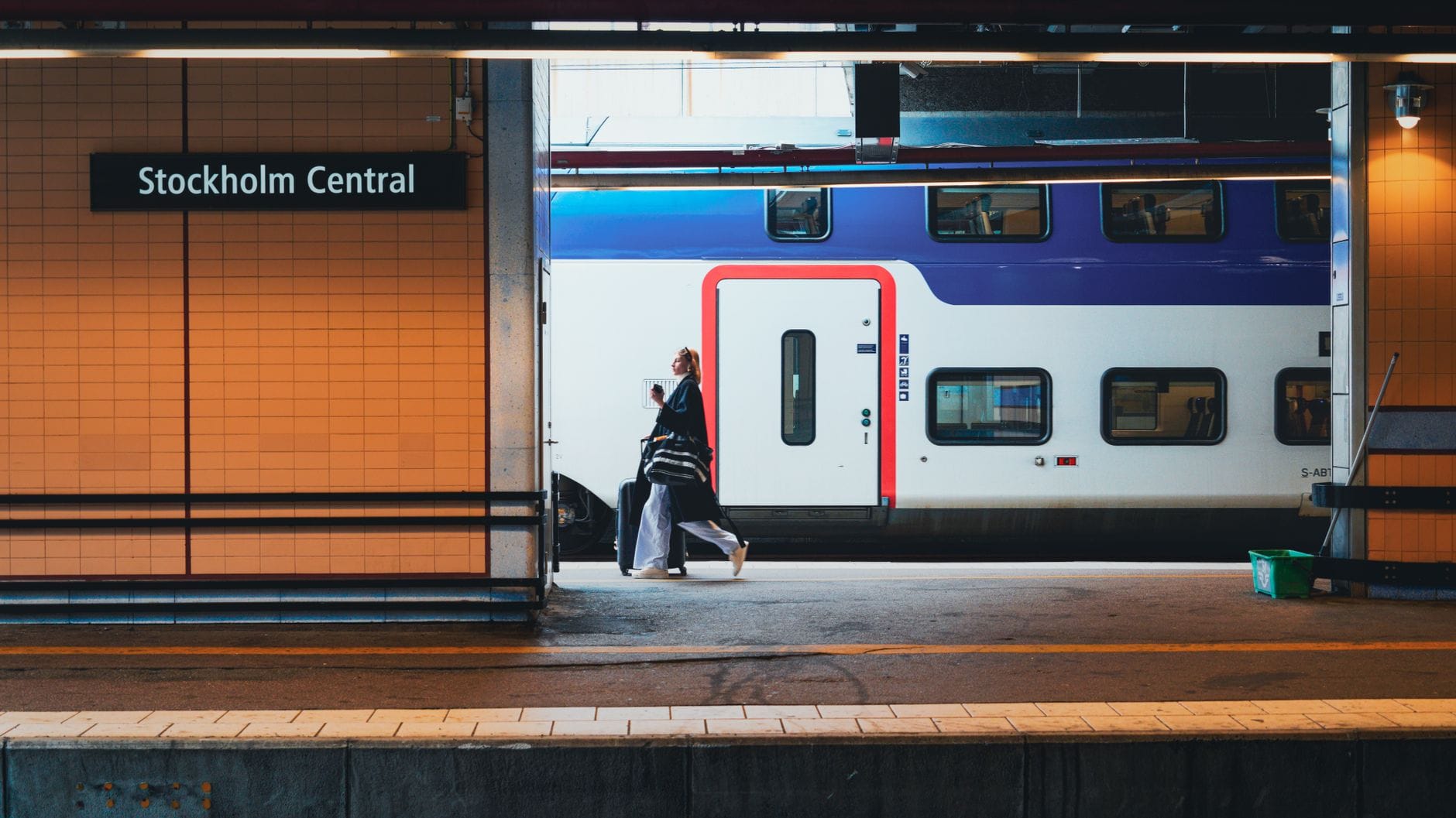 รถไฟสมัยใหม่ที่สถานี Stockholm Central พร้อมผู้โดยสารเดินบนชานชาลา และป้าย Stockholm Central ที่มองเห็นได้ชัดเจน