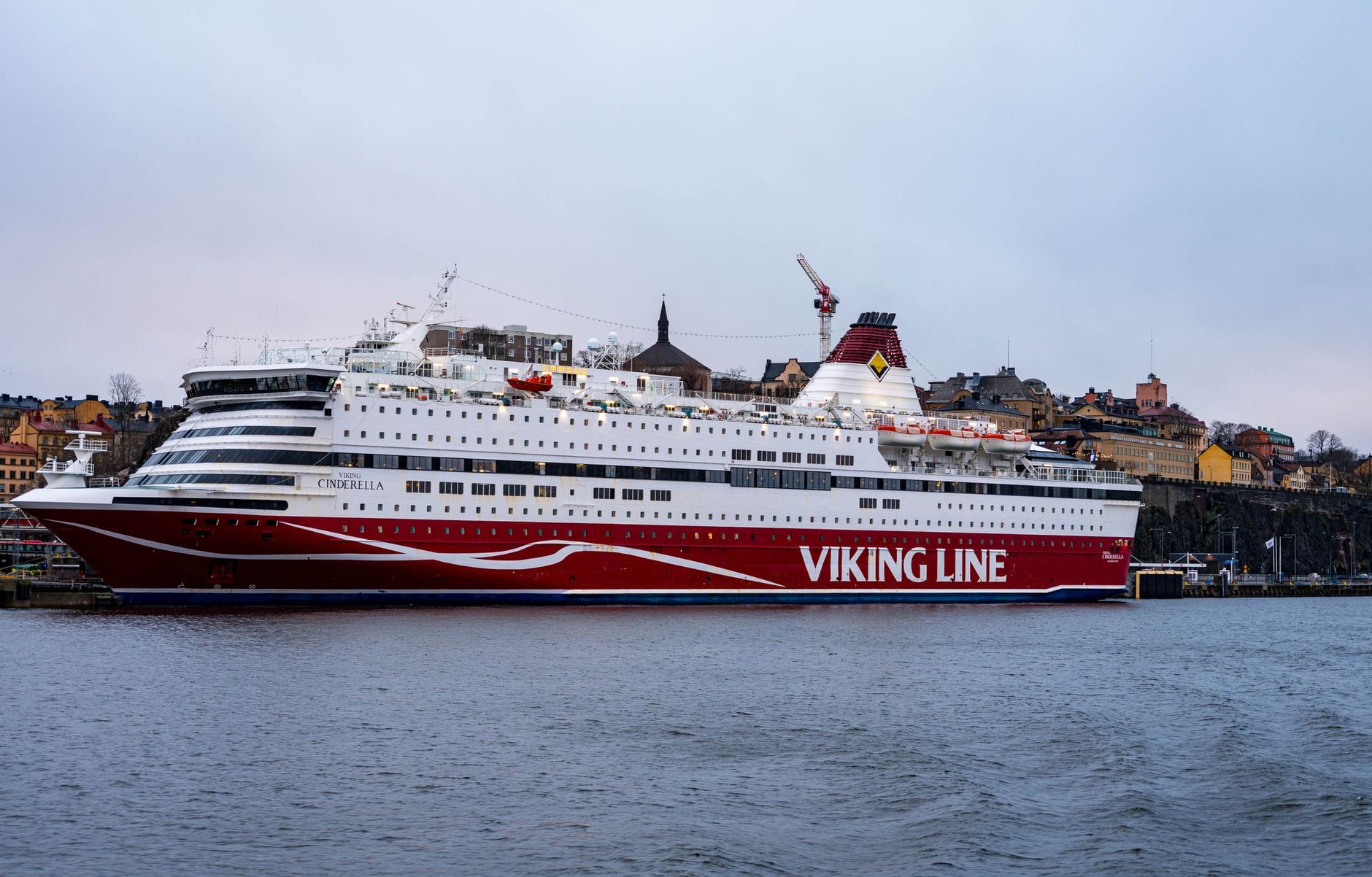 เรือเฟอร์รี่ Viking Line ลำใหญ่จอดอยู่ที่ท่าเรือสตอกโฮล์ม มีอาคารเมืองเก่าเป็นฉากหลัง สะท้อนเส้นทางเฟอร์รี่สตอกโฮล์ม-เฮลซิงกิสุดคลาสสิก
