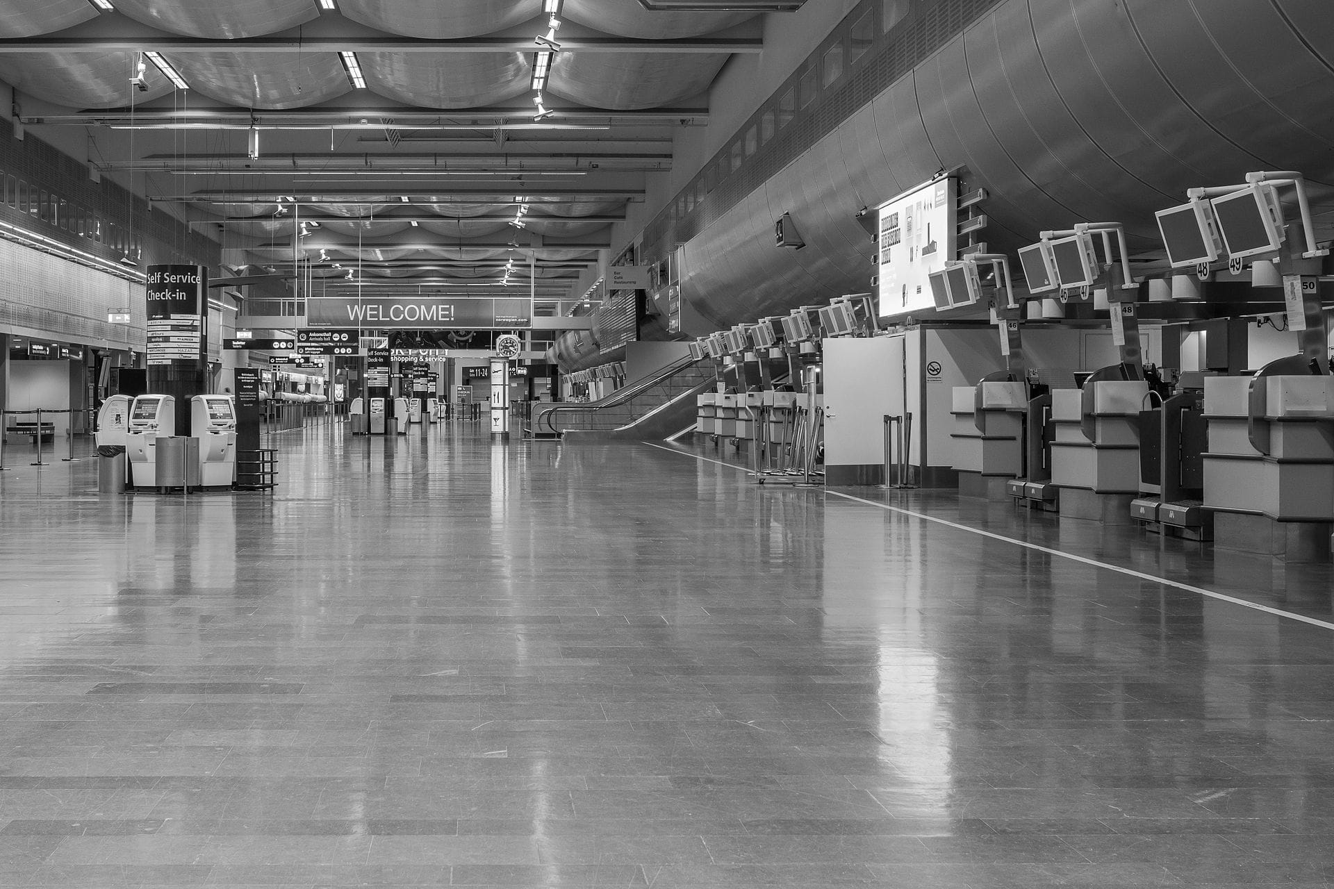 ภาพมุมกว้างขาวดำของภายในอาคารผู้โดยสารสนามบิน Stockholm Arlanda พร้อมตู้เช็คอินและป้ายต้อนรับ