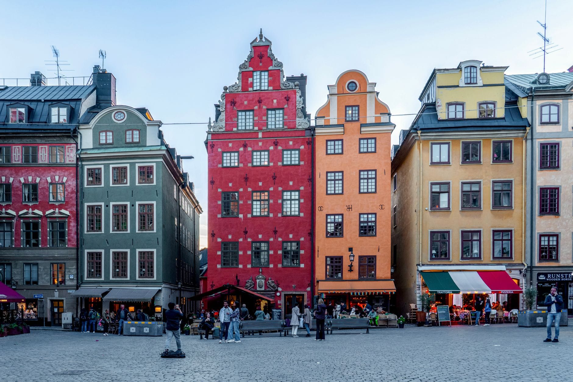 อาคารสีสันสดใสในศตวรรษที่ 17 หันหน้าสู่จัตุรัสคึกคักใน Gamla Stan กรุงสตอกโฮล์ม พร้อมผู้คนและร้านกาแฟกลางแจ้ง