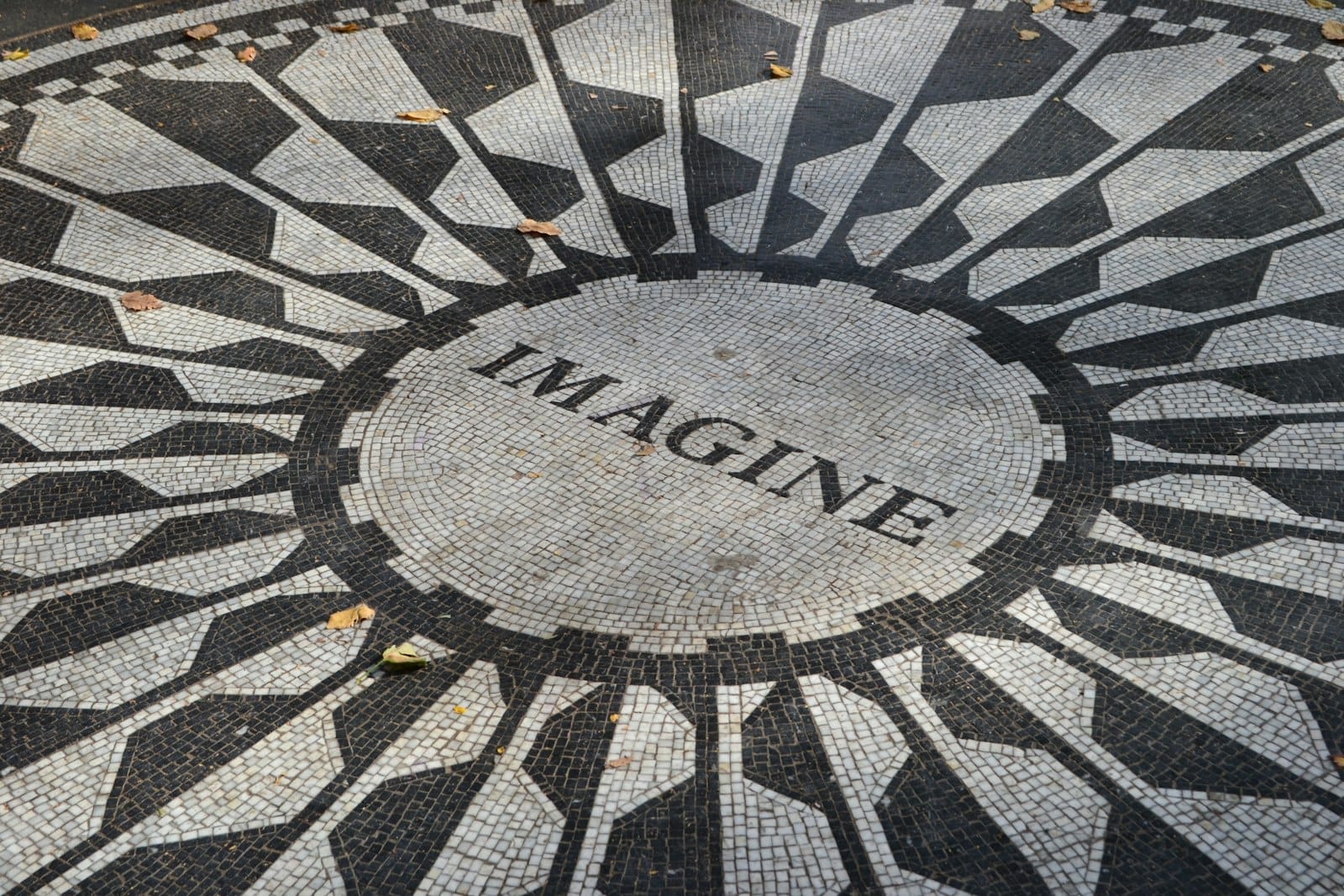 Vista ravvicinata dell'iconico mosaico Imagine a Strawberry Fields, nel memoriale di Central Park, con la luce del sole e qualche foglia autunnale sparsa.