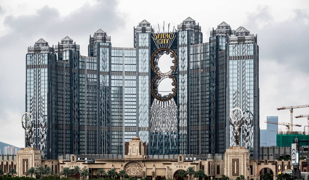 Außenansicht des Studio City Macau mit seinen markanten Art-déco-Türmen und dem Golden Reel Riesenrad in Achterform, das in die Fassade integriert ist.