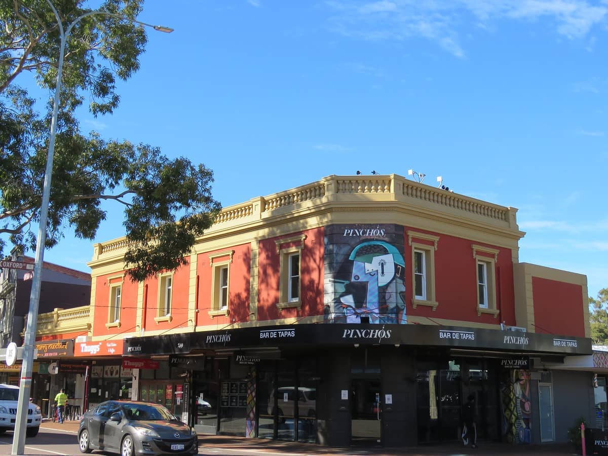 อาคารประวัติศาสตร์สีแดงและเหลืองบน Oxford Street ใน Leederville พร้อมงานศิลปะบนท้องถนนและ Pinchos Bar de Tapas ใต้ท้องฟ้าสีฟ้าใส