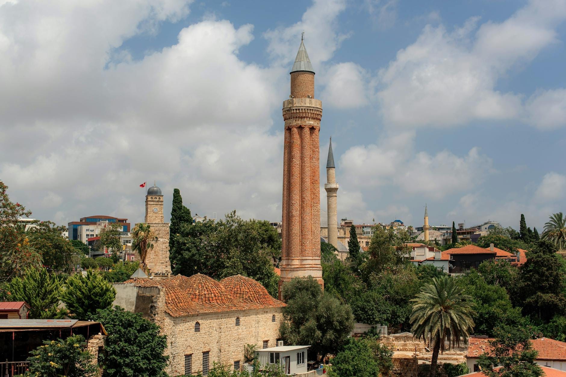 Vista diurna della storica Moschea di Sultan Alaaddin con il suo iconico minareto scanalato che si erge sui tetti del centro storico di Kaleiçi e sulle palme di Antalya.