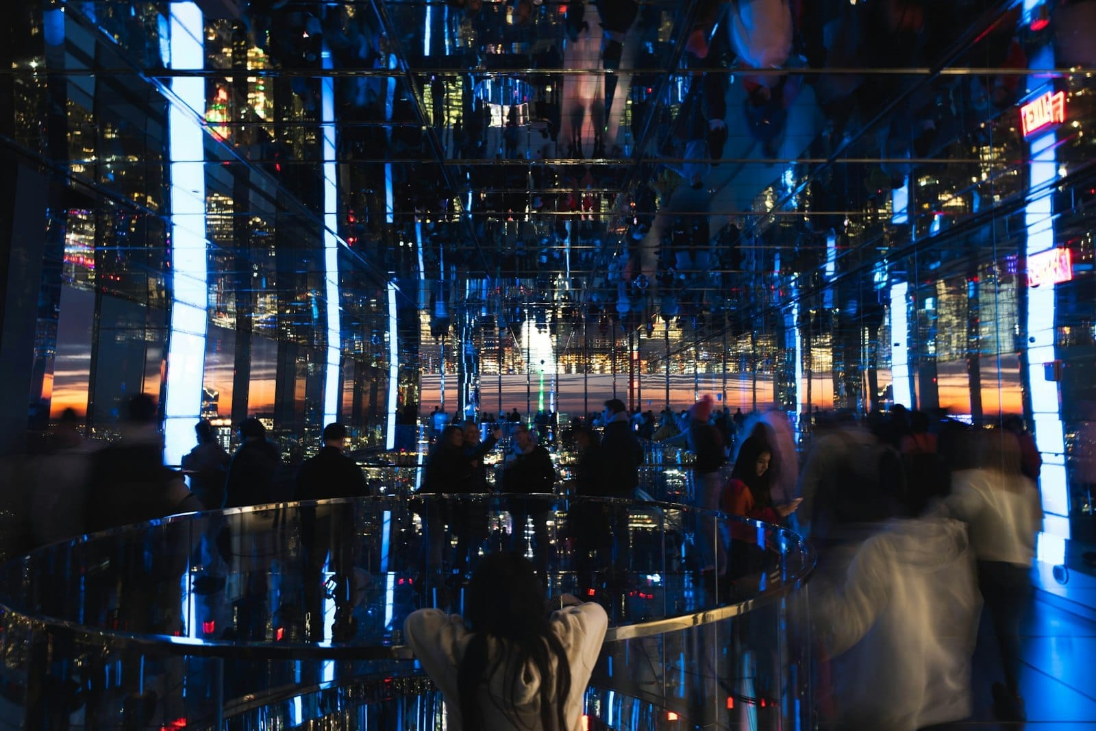 I visitatori esplorano un'installazione artistica immersiva con specchi al tramonto all'interno di SUMMIT One Vanderbilt: le luci della città e i riflessi amplificano l'atmosfera futuristica dell'osservatorio.