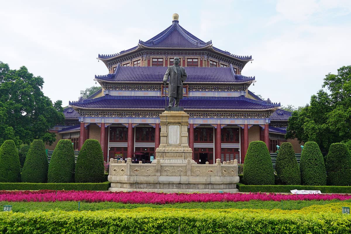 Front view of Sun Yat-sen Memorial Hall in Guangzhou featuring the grand octagonal structure and a statue of Sun Yat-sen in the foreground, surrounded by landscaped gardens.