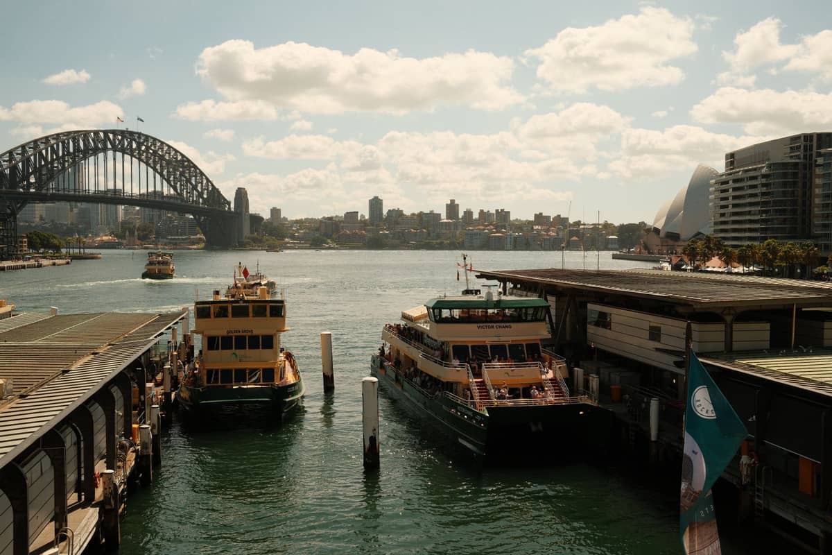 Fähren des Sydney Harbour am Circular Quay angedockt, mit der Harbour Bridge und dem Opera House im Hintergrund.