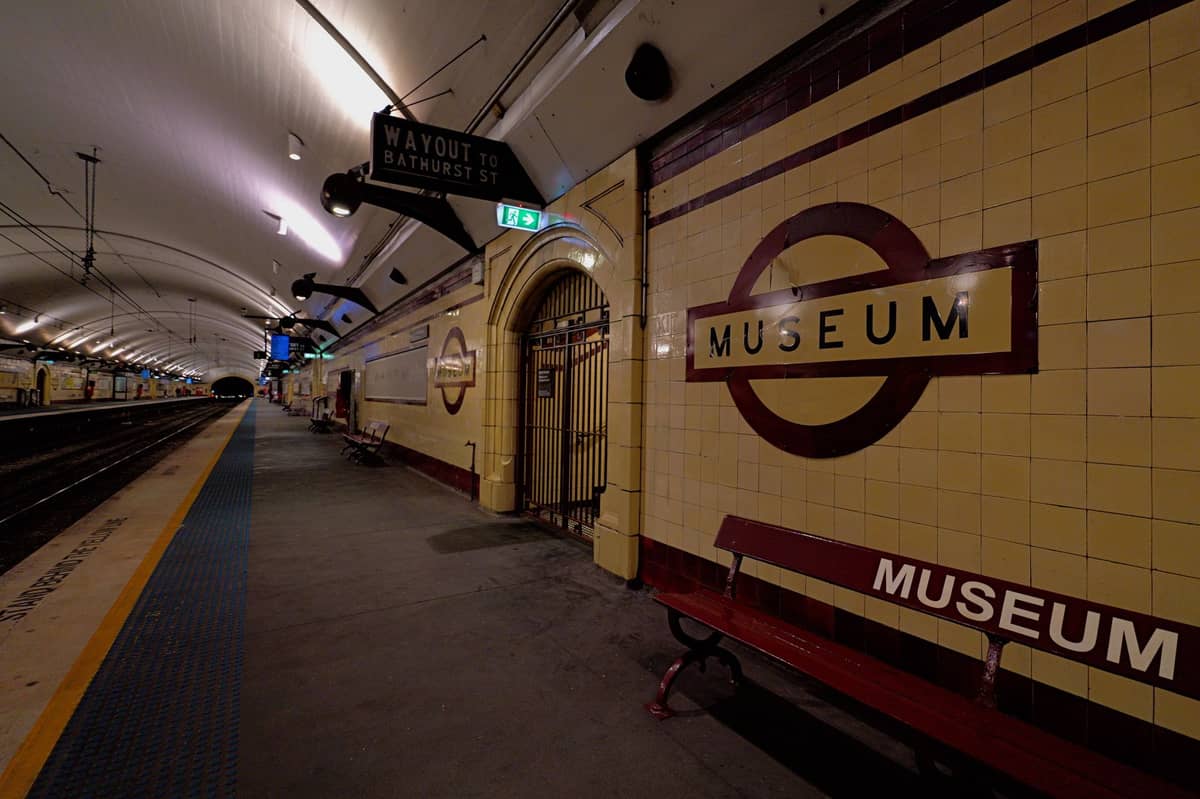 Bahnsteig der Museum Station in Sydney mit gefliesten Wänden, großen 'Museum'-Schildern, gewölbter Decke und Bahnsteigbeschilderung – eine wichtige Haltestelle in der Nähe der Mardi-Gras-Feierlichkeiten.