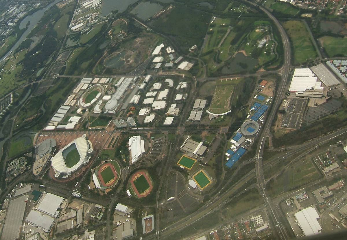 Vista aerea di Sydney Olympic Park con stadi, arene sportive, grandi spazi verdi e corsi d'acqua che compongono il comprensorio olimpico.
