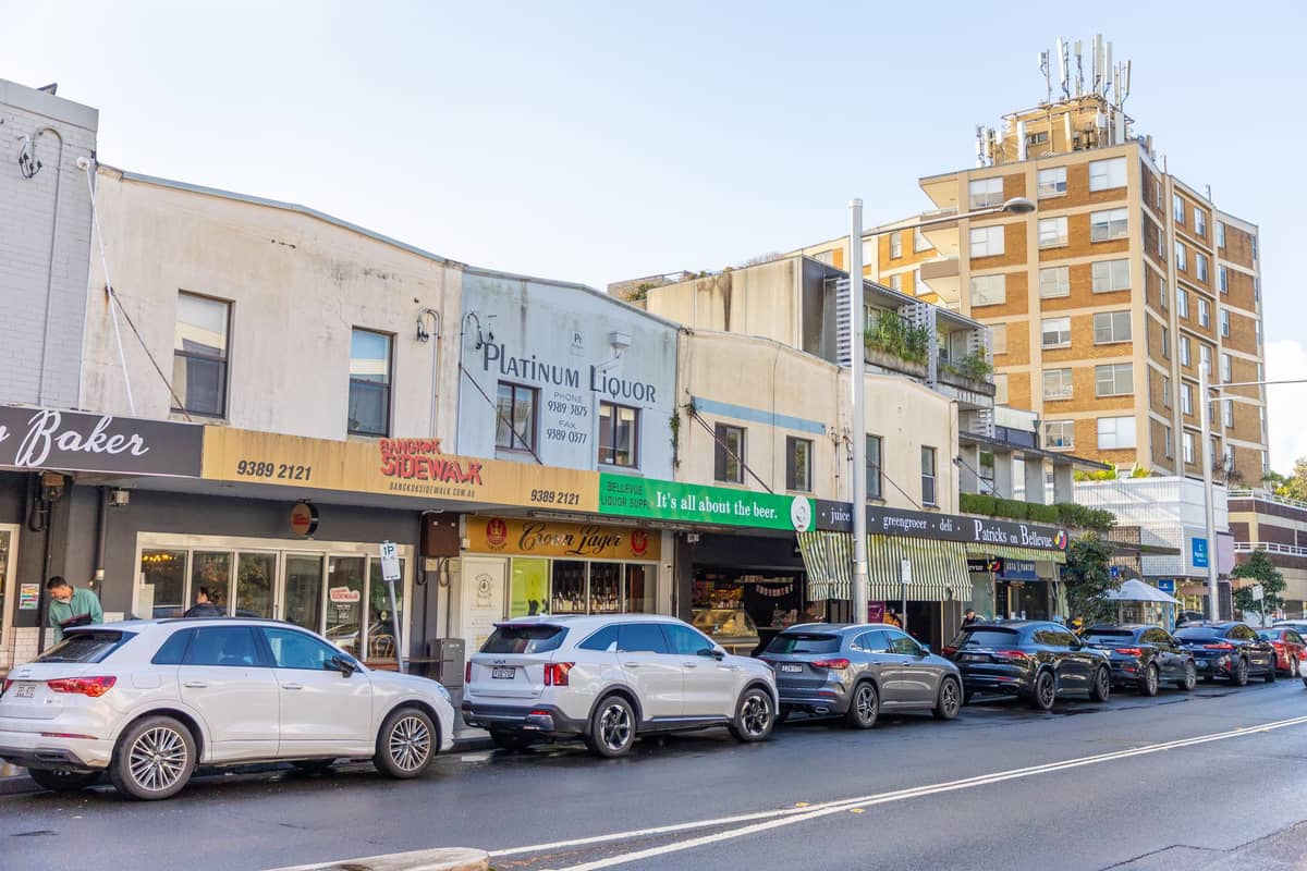 Street view of a small shopping strip with several cars parked and signs for various local businesses in a Sydney suburb.