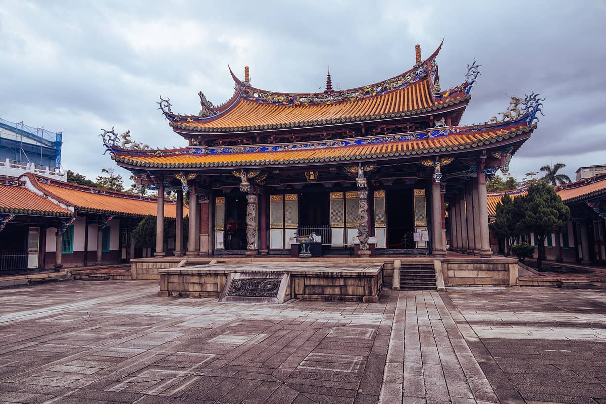 Weitwinkelperspektive auf die Haupthalle des Taipei Konfuzius-Tempels in Taiwan mit elegantem südlichen Fujian-Architekturstil, kunstvollen Dachverzierungen und einem offenen Innenhof unter bewölktem Himmel.