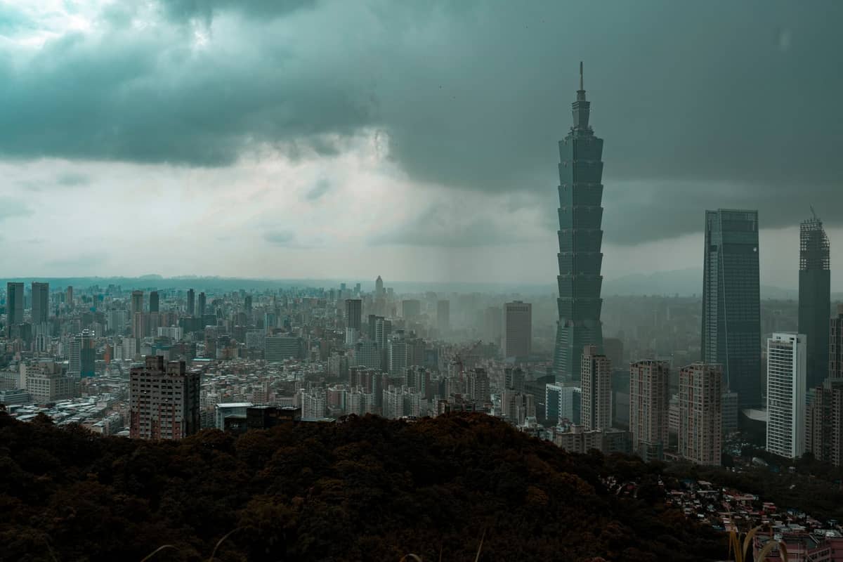 Skyline von Taipei an einem bewölkten Tag mit Taipei 101, der über die Gebäude ragt, von einem Hügel aus gesehen, unter düsteren Winterwolken.