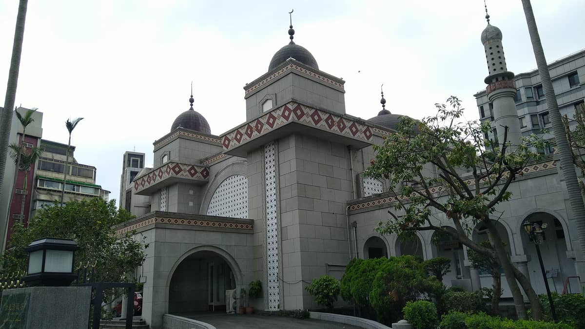 Außenansicht der Taipeh-Hauptmoschee mit Kuppeln, Minarett und nahöstlich geprägten Architekturdetails, umgeben von Bäumen und Stadtgebäuden.
