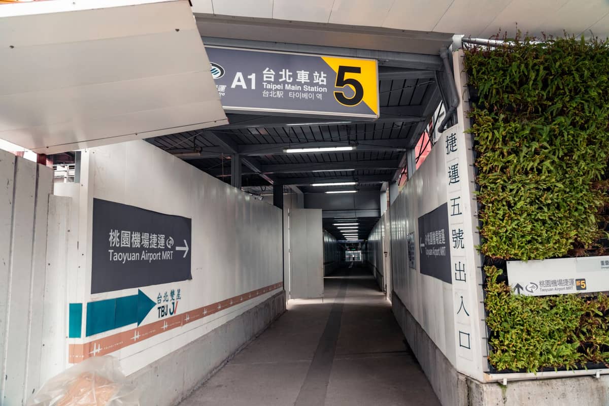 Überdachter Durchgang an der Taipei Main Station mit Schildern zum Taoyuan Airport MRT und zum Stationsausgang, mit klaren zweisprachigen Hinweisen.
