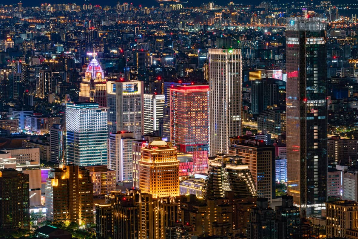 Nachtansicht des Xinyi-Viertels in Taipei mit hell erleuchteten Einkaufszentren, Bürohochhäusern und Kaufhäusern im Stadtzentrum.