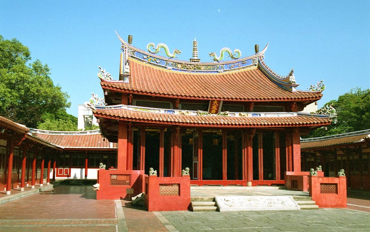 Innenhofansicht des Konfuzius-Tempels Taipei mit verziertem roten Dach, Drachenskulpturen und traditioneller Architektur im Sonnenlicht.