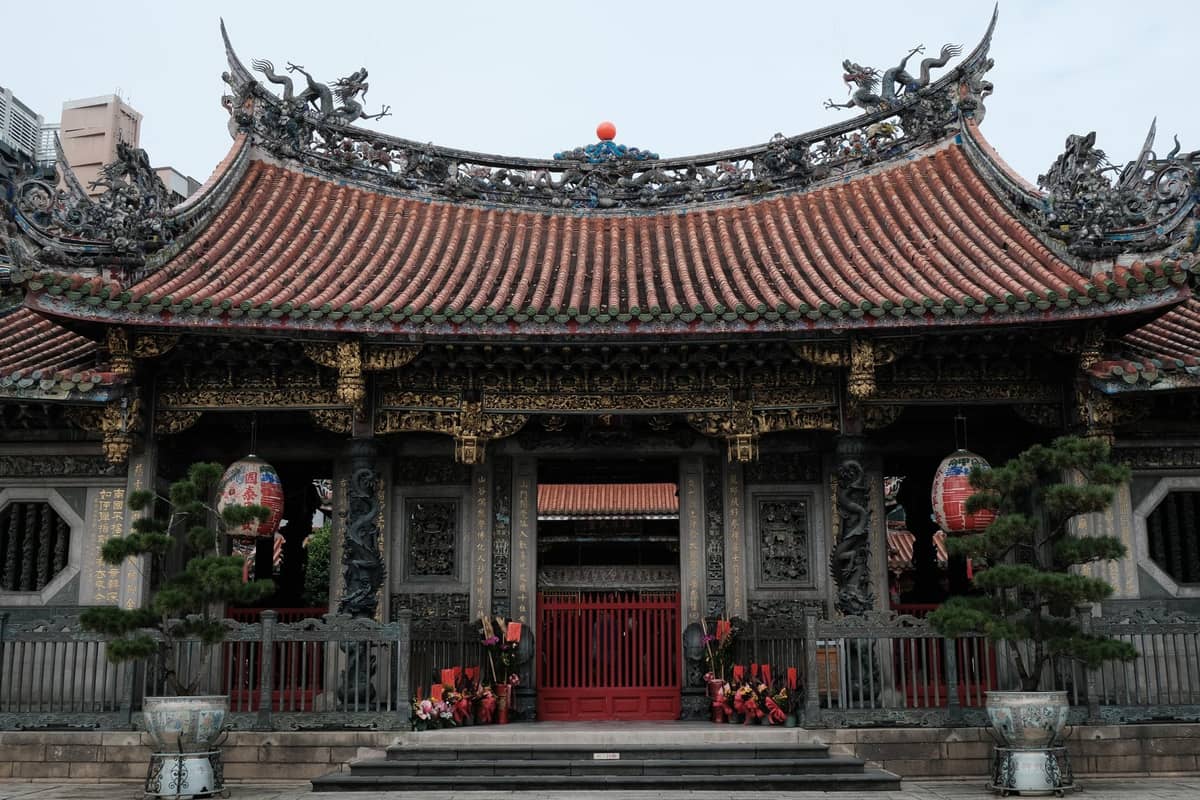 Vorderansicht eines prächtigen traditionellen chinesischen Tempels mit verziertem Dach und roten Türen in Taipei.