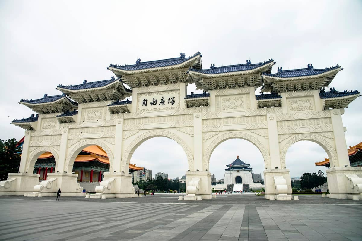 Weitwinkelansicht des Tores des Liberty Square in Taipei mit fünf blau überdachten Bögen, dem Denkmal im Hintergrund und einem weitläufigen öffentlichen Platz davor.