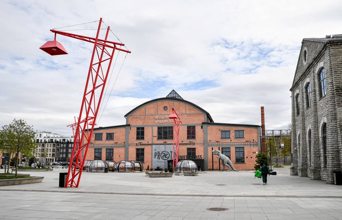 Grande scultura rossa ed edificio in stile industriale nella Telliskivi Creative City, Tallinn, un popolare polo per la cultura e le arti locali.
