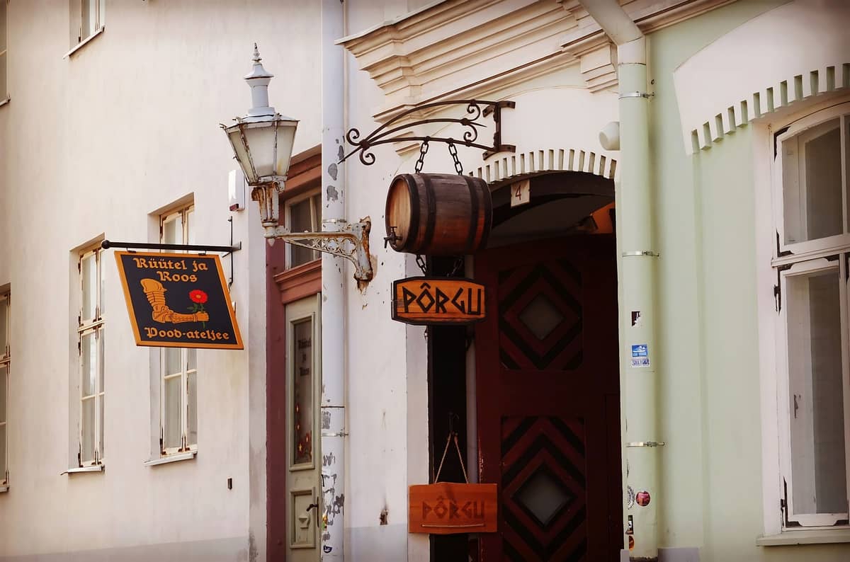 Eingang zu einer Bar in der Tallinner Altstadt mit einem Fassschild und einer hängenden Laterne, authentischer estnischer Beschilderung und Architektur im alten Stil.
