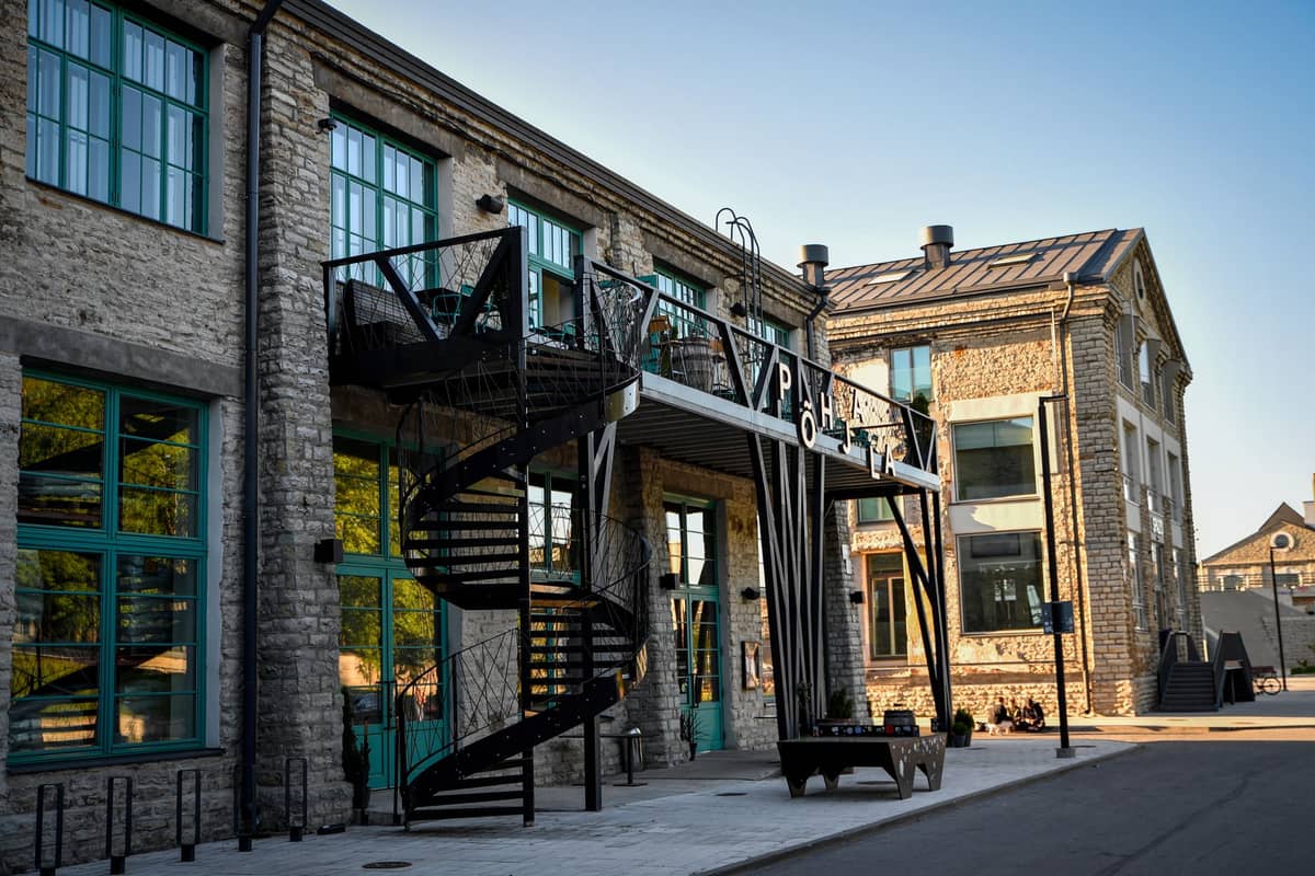 Industriell gestaltetes Steingebäude mit Wendeltreppe und blau gerahmten Fenstern in der Telliskivi Creative City, bekannt für unabhängige Bars und Tallinns Craft-Beer-Szene.