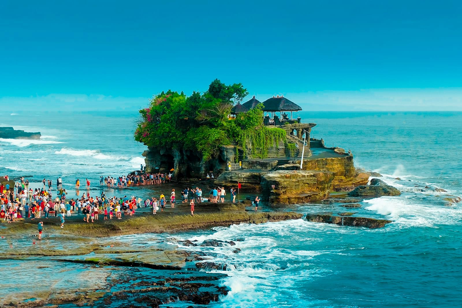 Il tempio marino di Tanah Lot con la bassa marea e visitatori che camminano sulle rocce costiere, Bali