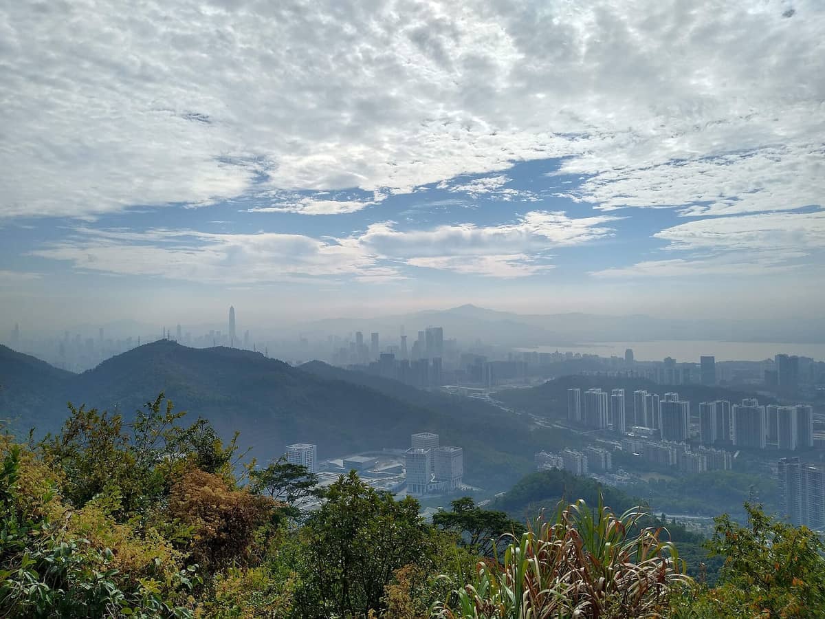 Vista do horizonte de Shenzhen e seus modernos arranha-céus a partir de um exuberante ponto de observação verde no Parque Natural da Montanha Tanglang sob um céu dramático.