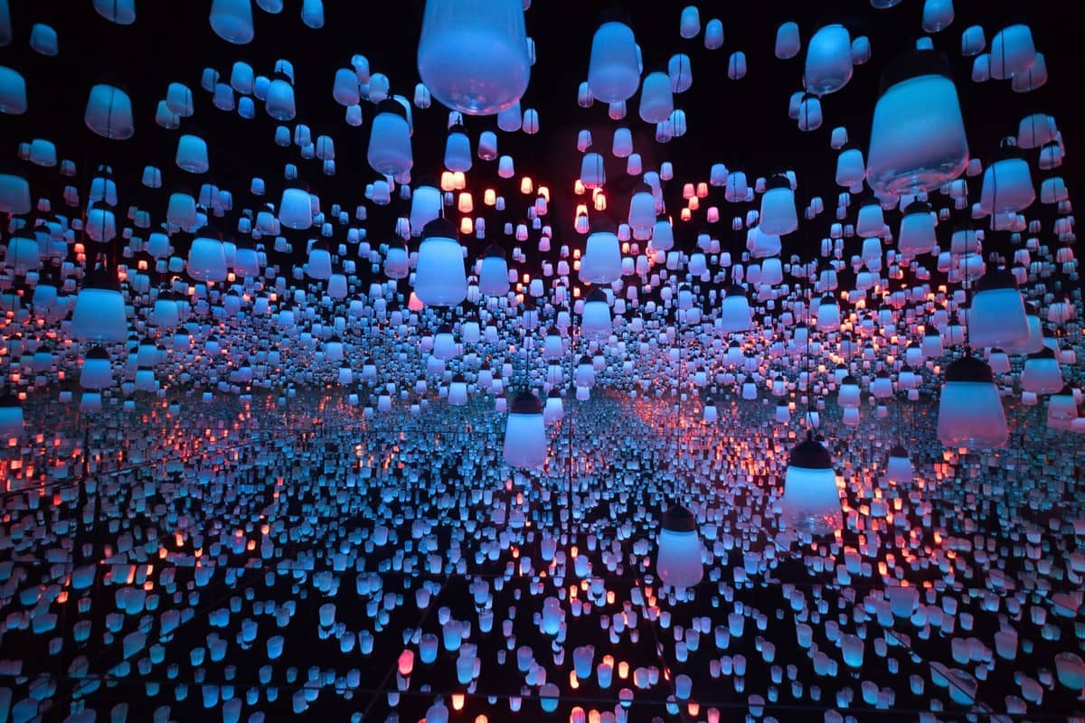 Hundreds of glowing lanterns suspended from the ceiling create an immersive digital art installation at teamLab Biovortex Kyoto, reflecting endlessly in mirrored walls.
