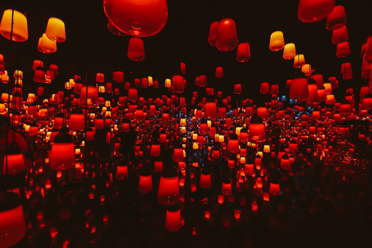 Immersive room filled with glowing red and orange hanging lanterns reflected in mirrored walls at teamLab Borderless or Planets in Tokyo.