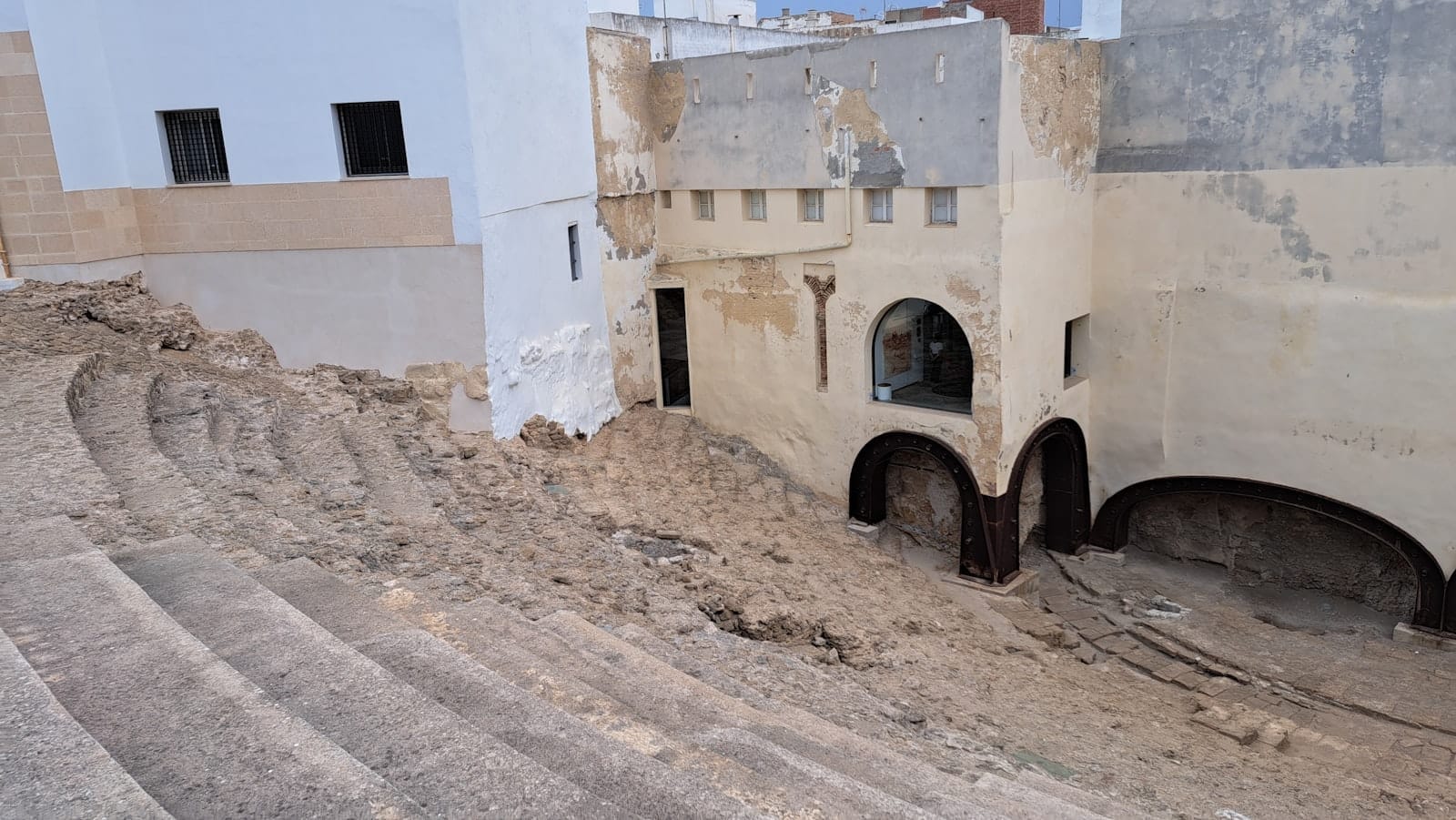 Gradinate in pietra e resti dell'antico Teatro Romano di Cádiz inglobati nella città, con l'architettura romana scavata affiancata agli edifici moderni.