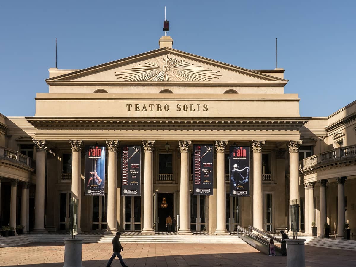 Teatro Solís สไตล์นีโอคลาสสิกอันยิ่งใหญ่ในมอนเตวิเดโอ โดดเด่นด้วยเสาสูง ป้ายการแสดง และท้องฟ้าสีฟ้าใสเหนือด้านหน้าอาคารประวัติศาสตร์