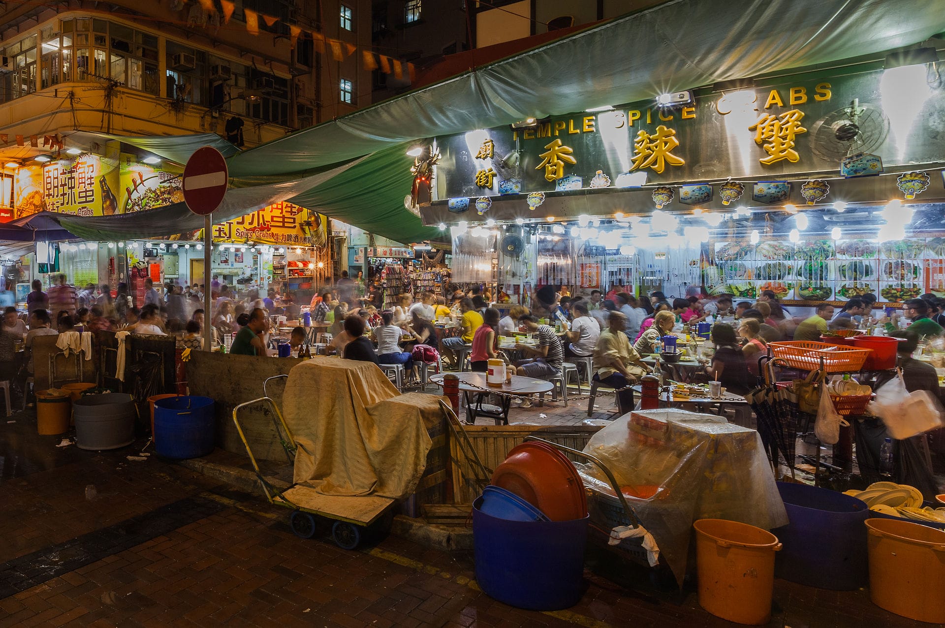 Vista atmosferica del Mercato Notturno di Temple Street a Hong Kong con persone che mangiano, fanno shopping e passeggiano.